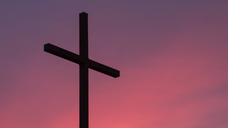 A silhouette of a cross on a sunset background
