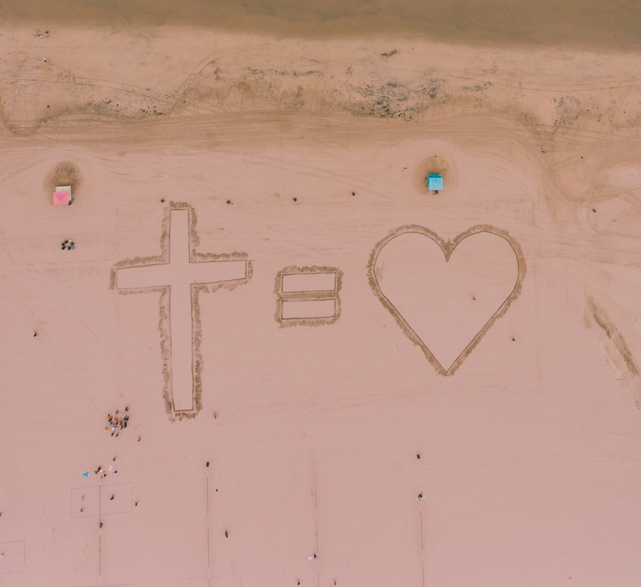 "the cross = love" written in the sand