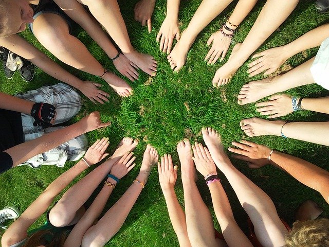 People sat on the grass, putting hands and feet together to make a circle