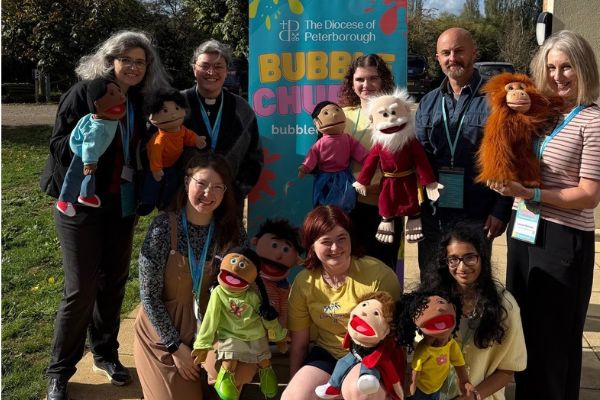 Bubble Church team members pose outdoors with a collection of puppets in front of a colourful Bubble Church banner.